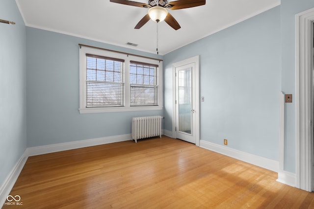 empty room featuring hardwood / wood-style flooring, radiator, and ceiling fan