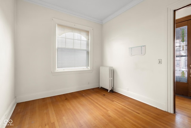 empty room with radiator, ornamental molding, and light hardwood / wood-style flooring