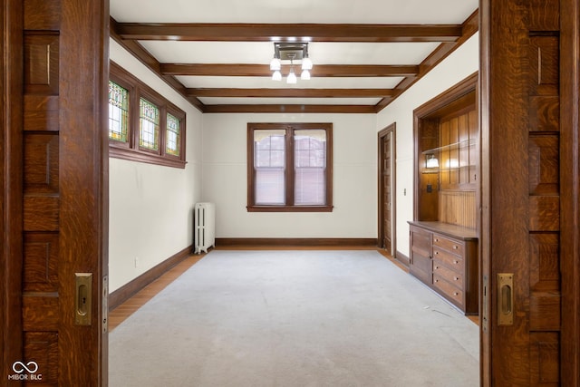 spare room featuring light colored carpet, radiator heating unit, and beam ceiling