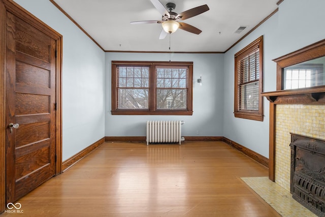 unfurnished living room with ceiling fan, radiator, ornamental molding, and light hardwood / wood-style flooring