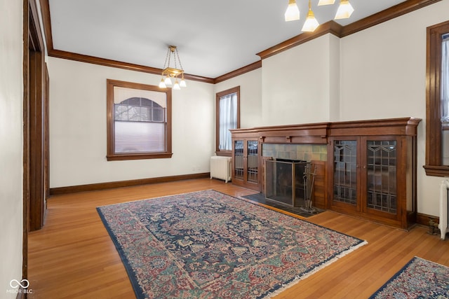 living room featuring radiator, a chandelier, light hardwood / wood-style floors, and ornamental molding