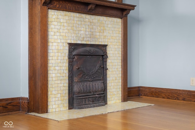 details with a tile fireplace and hardwood / wood-style flooring