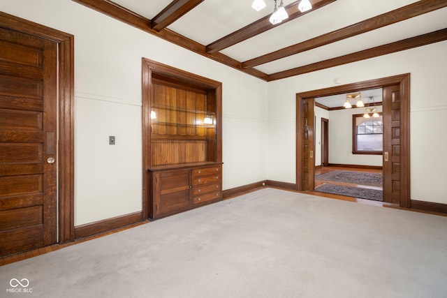 carpeted empty room featuring beam ceiling