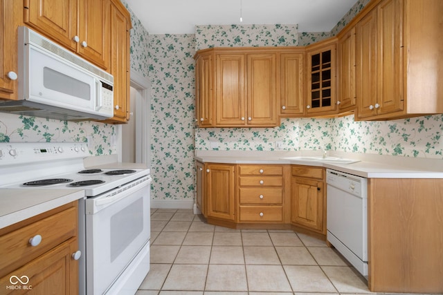 kitchen featuring sink, light tile patterned flooring, and white appliances