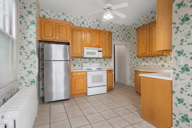 kitchen featuring ceiling fan, radiator, light tile patterned flooring, and white appliances