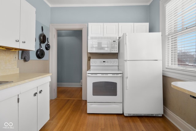 kitchen with backsplash, white appliances, white cabinets, ornamental molding, and light hardwood / wood-style flooring