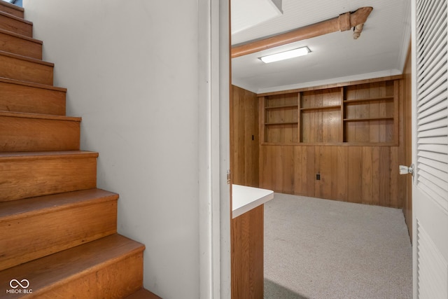 stairs with crown molding and carpet flooring