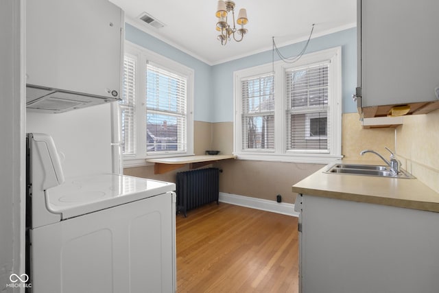 interior space with sink, an inviting chandelier, white cabinetry, radiator, and range