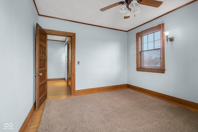 carpeted spare room with ceiling fan and crown molding