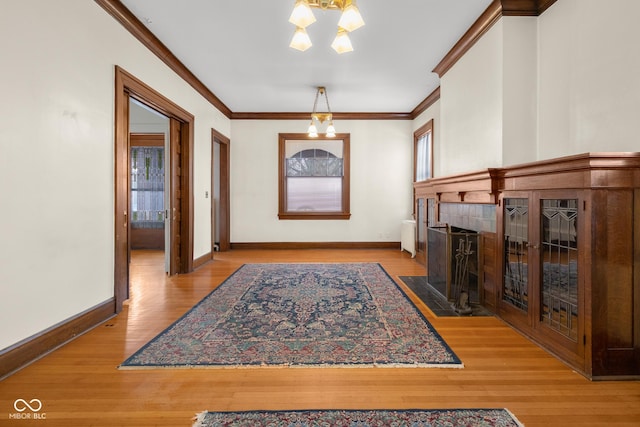 entrance foyer with an inviting chandelier, ornamental molding, and hardwood / wood-style floors