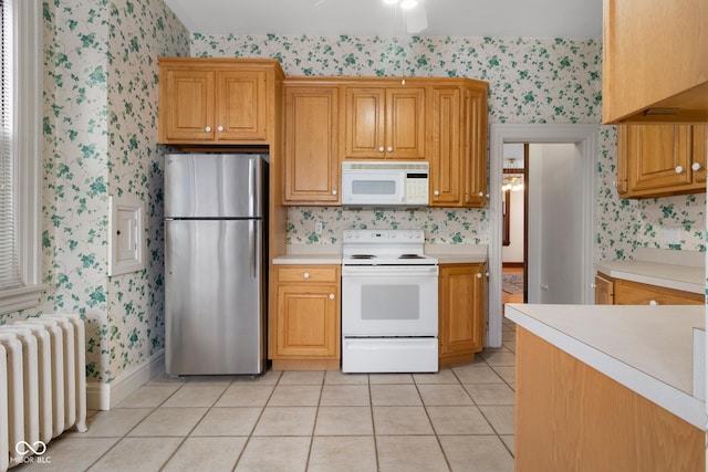 kitchen with ceiling fan, white appliances, radiator heating unit, and light tile patterned flooring