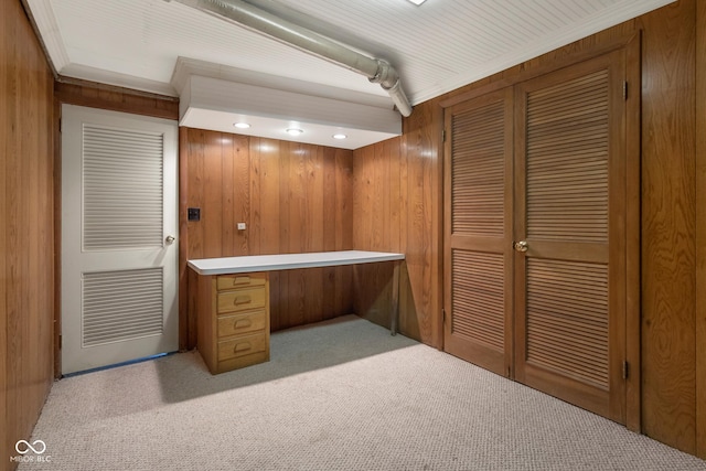 unfurnished office featuring crown molding, light colored carpet, and wooden walls