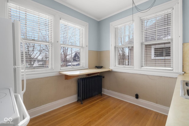 interior space with radiator, plenty of natural light, ornamental molding, and hardwood / wood-style floors