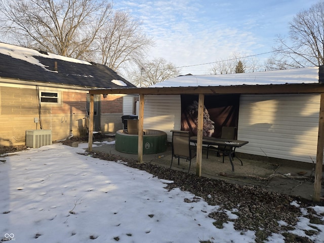 snow covered house featuring central AC unit