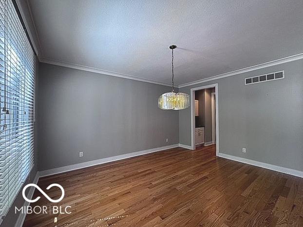 13650 Golden Ridge Ln, Fishers, IN 46055 - spare room featuring dark wood-style floors, ornamental molding, a chandelier, and a textured ceiling