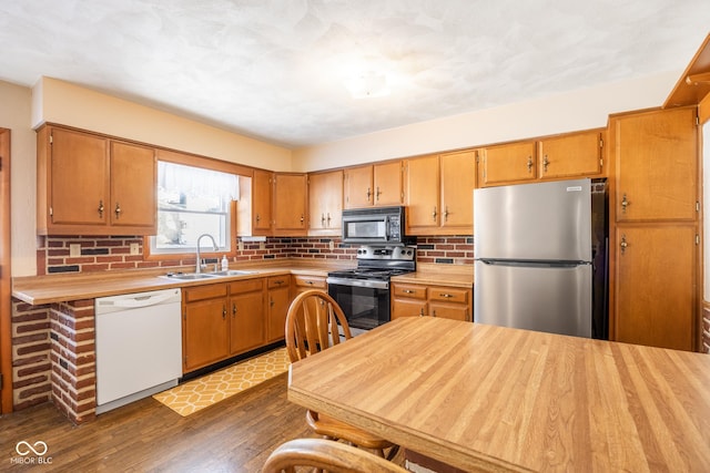 kitchen with dark wood-type flooring, sink, backsplash, and stainless steel appliances