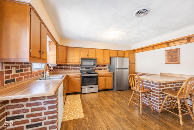 kitchen featuring sink, stainless steel appliances, light wood-type flooring, and backsplash