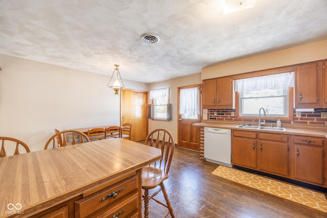 kitchen featuring dishwasher, sink, decorative light fixtures, dark wood-type flooring, and backsplash