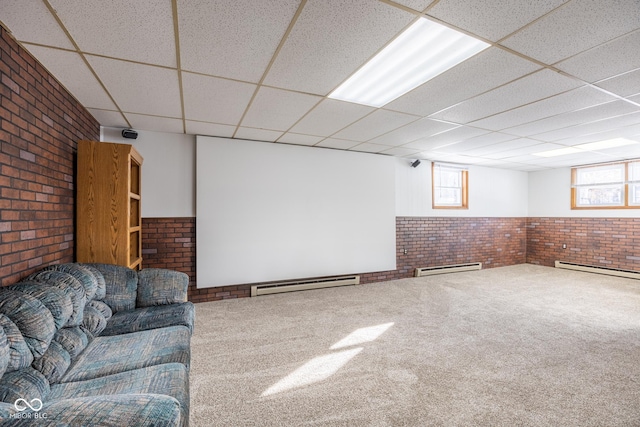 basement featuring a baseboard radiator, brick wall, and a paneled ceiling