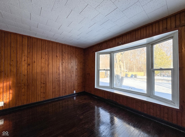 unfurnished room featuring dark hardwood / wood-style floors and wood walls