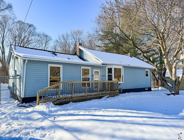 snow covered back of property featuring a deck