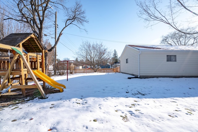 snowy yard featuring a playground