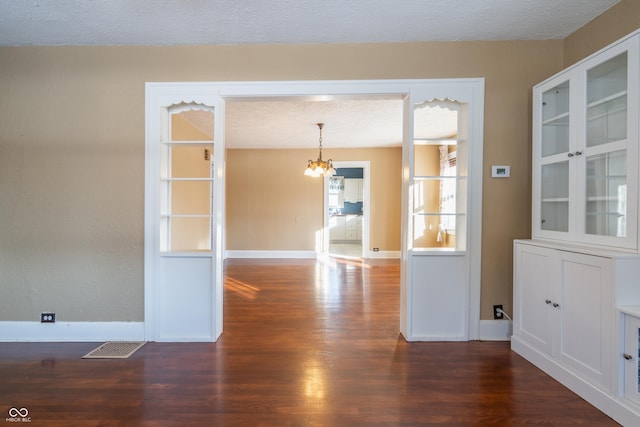 unfurnished dining area featuring dark wood-type flooring and a chandelier