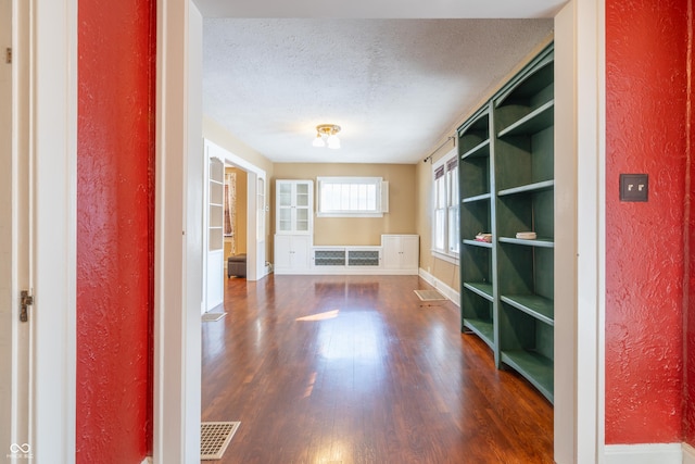 hall with dark wood-type flooring and a textured ceiling