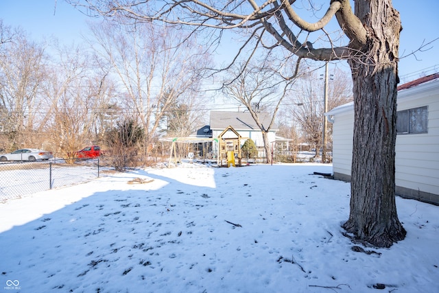 snowy yard featuring a playground