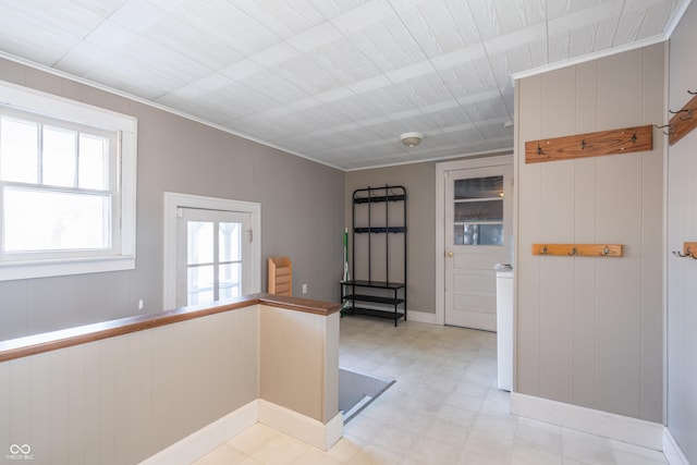 foyer with ornamental molding and wooden walls