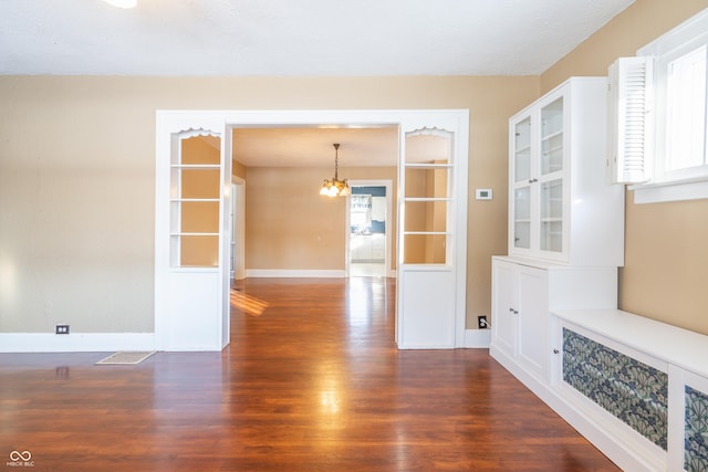 interior space with dark hardwood / wood-style floors, a wealth of natural light, and an inviting chandelier