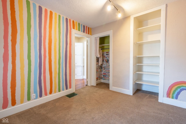 unfurnished bedroom featuring carpet floors, a textured ceiling, and rail lighting