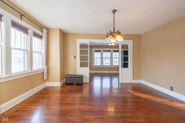 unfurnished dining area with a textured ceiling, dark hardwood / wood-style floors, and a healthy amount of sunlight