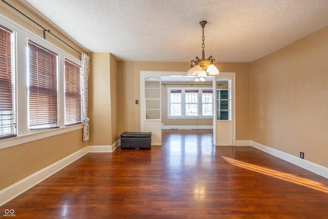 interior space with a textured ceiling, dark wood-type flooring, and an inviting chandelier