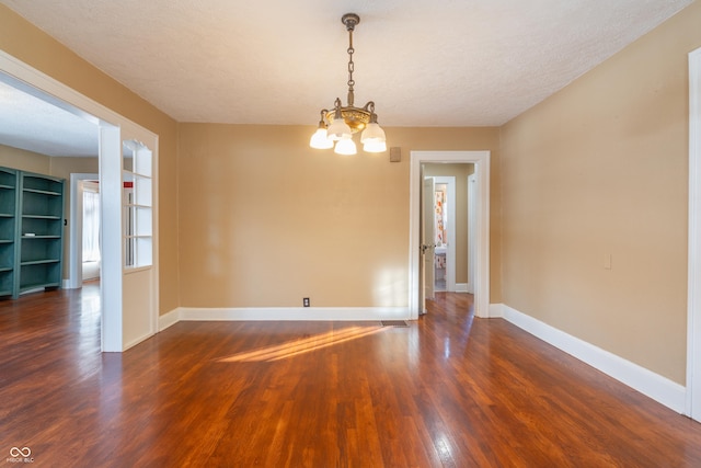 spare room with a textured ceiling, dark hardwood / wood-style flooring, and a notable chandelier