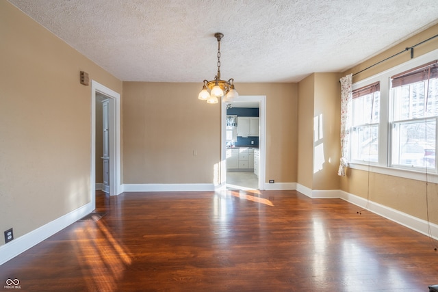 unfurnished dining area featuring dark hardwood / wood-style floors, an inviting chandelier, and a textured ceiling