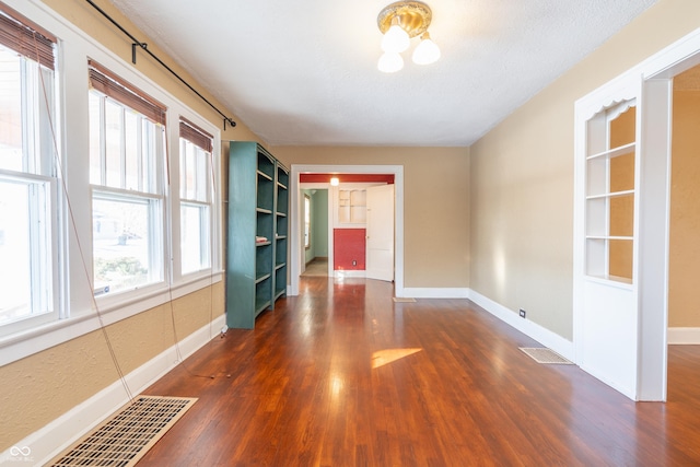 empty room featuring a textured ceiling and dark hardwood / wood-style floors