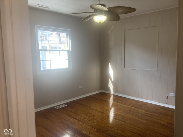 unfurnished room with ceiling fan, dark hardwood / wood-style floors, and wood walls