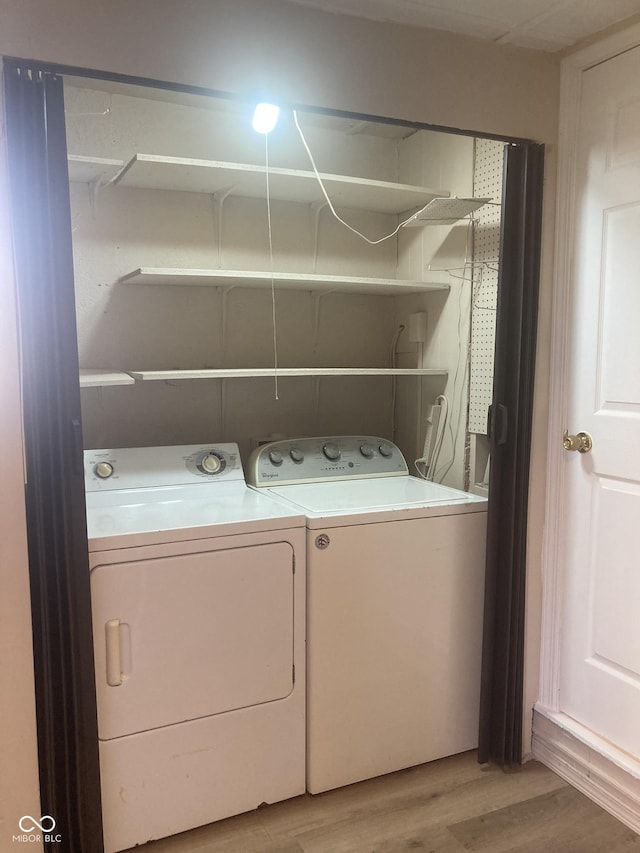 clothes washing area featuring washing machine and dryer and light hardwood / wood-style flooring