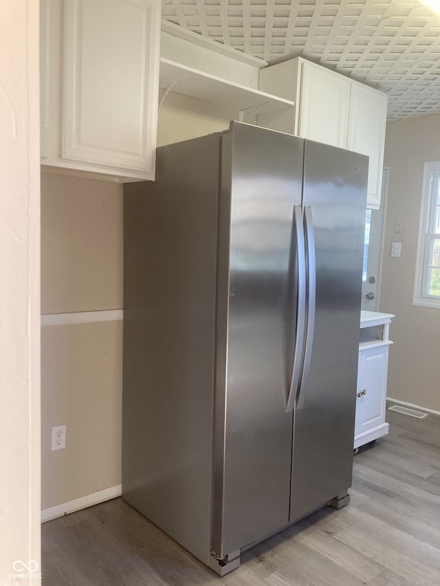 kitchen featuring white cabinets, light wood-type flooring, and stainless steel refrigerator