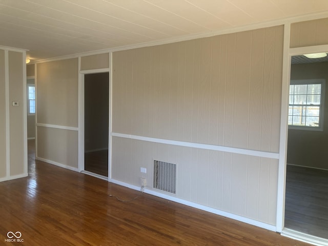 empty room with dark hardwood / wood-style flooring and crown molding