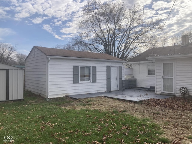 rear view of property featuring a patio area, a lawn, and a shed