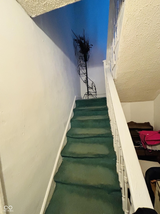 stairway featuring a textured ceiling and vaulted ceiling