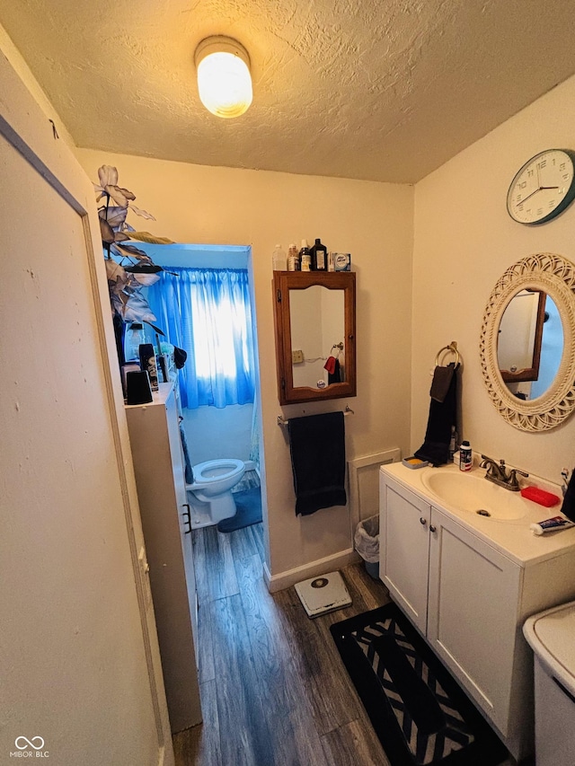 bathroom featuring toilet, a textured ceiling, hardwood / wood-style floors, and vanity