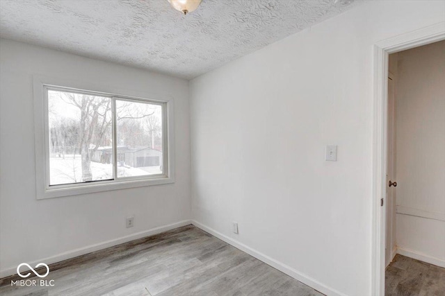 empty room with a textured ceiling and light hardwood / wood-style flooring