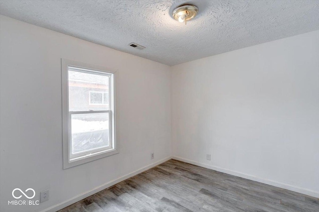 unfurnished room featuring wood-type flooring, plenty of natural light, and a textured ceiling