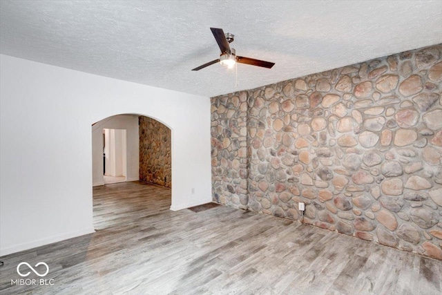 empty room with a textured ceiling, ceiling fan, and hardwood / wood-style flooring