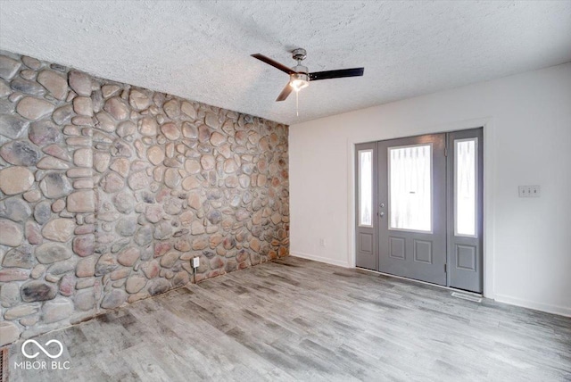 entryway with ceiling fan, light hardwood / wood-style floors, and a textured ceiling