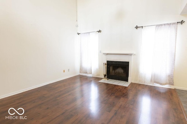 unfurnished living room featuring a tiled fireplace, hardwood / wood-style flooring, and a wealth of natural light