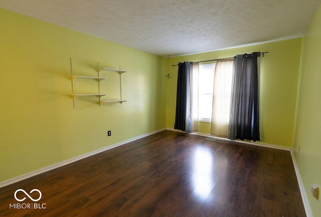 spare room featuring dark hardwood / wood-style floors and a textured ceiling